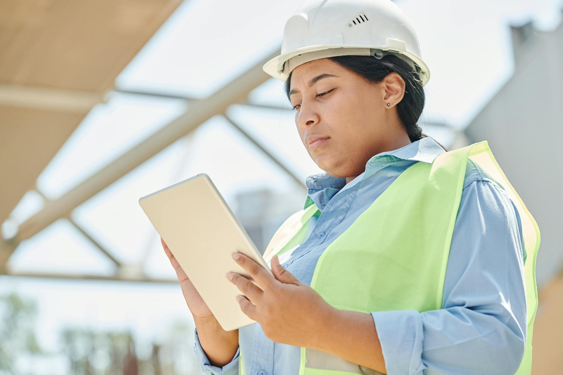 An engineer in a hard hat reviewing details on a tablet during a site survey
